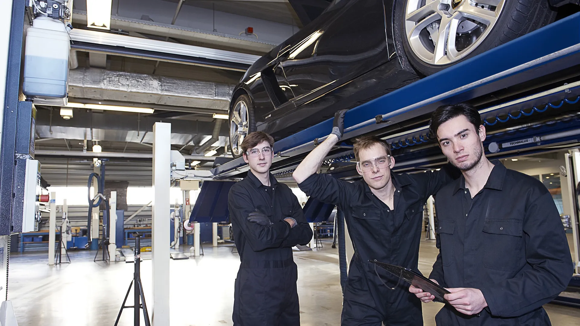 Drie monteurs staand onder de brug met een auto daarop