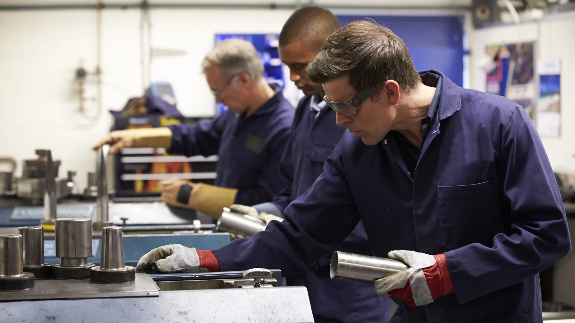 Drie medewerkers met metalen buizen aan het werk