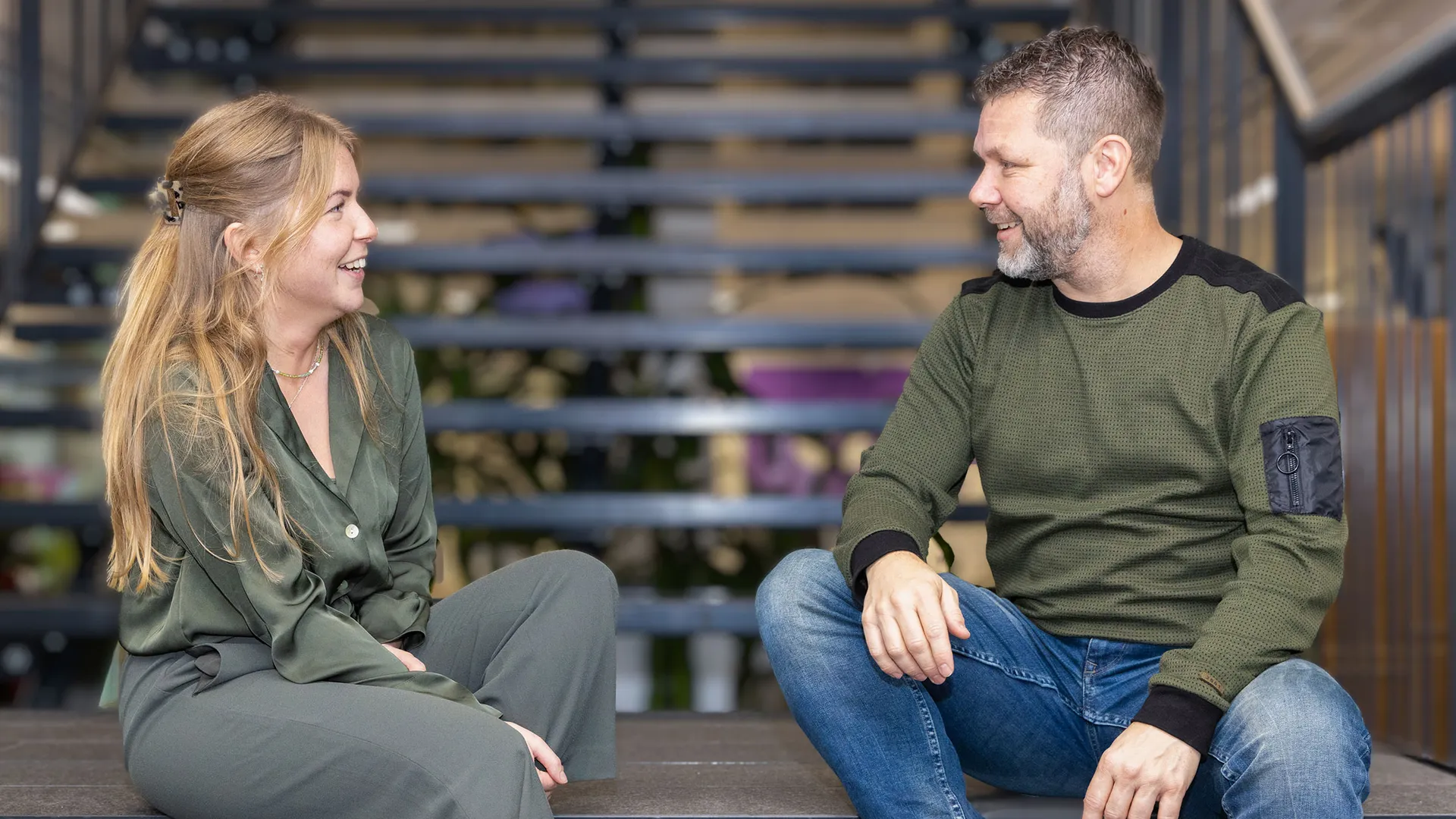 Twee collega's zittend op de trap in gesprek