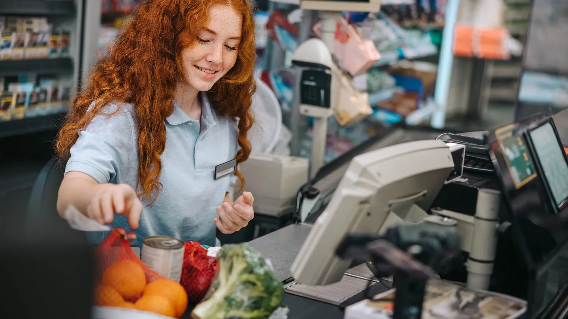 Jongere medewerkster achter de kassa van de supermarkt