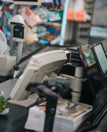 Jongere medewerkster achter de kassa van de supermarkt