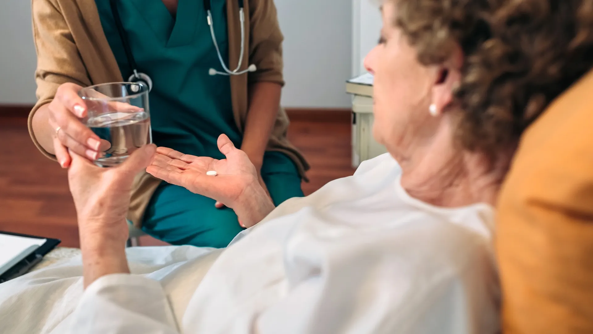 Vrouw liggend in bed krijgt van arts medicijn aangereikt