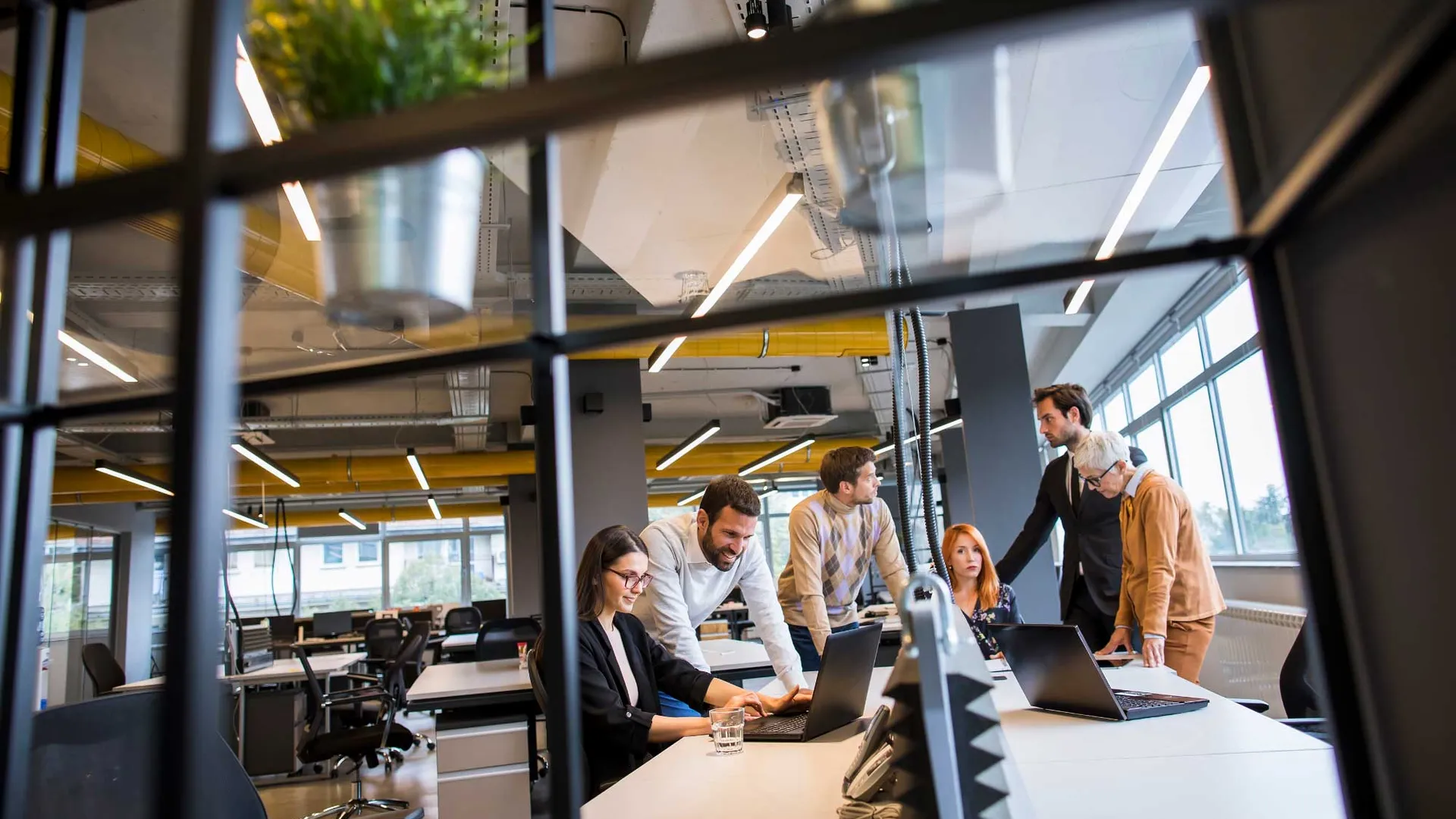 Zes collega's rondom een bureau met elkaar in gesprek