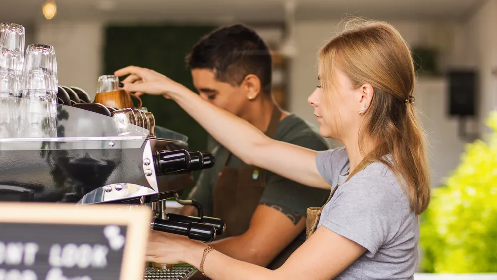 Twee horecamedewerkers bij een koffie-automaat