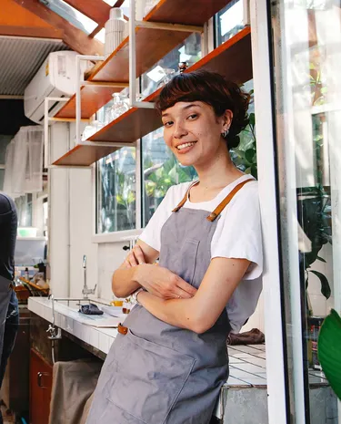 Twee horecamedewerkers staan achter de toonbank bij koffieapparaat.