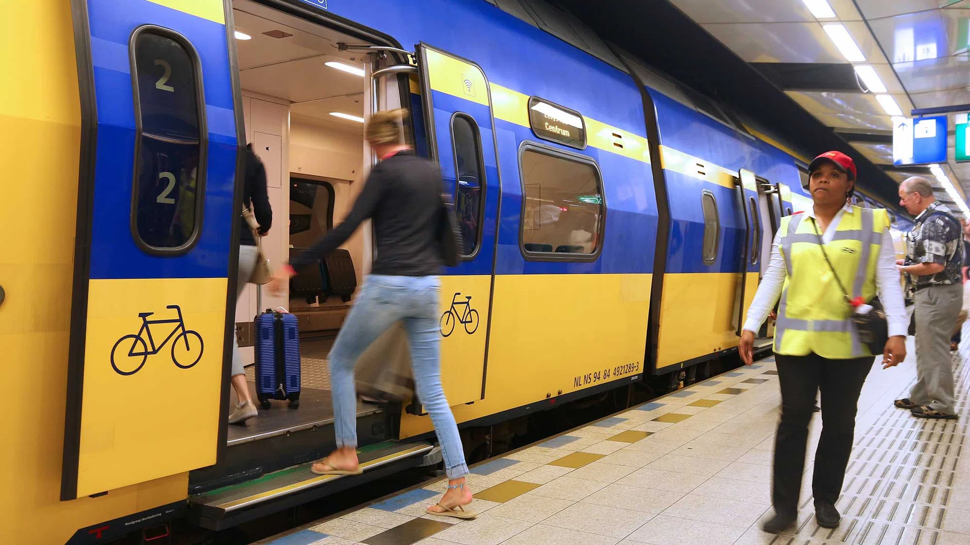 Medewerker van de NS loopt over het perron naast een stilstaande trein