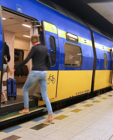 Medewerker van de NS loopt over het perron naast een stilstaande trein