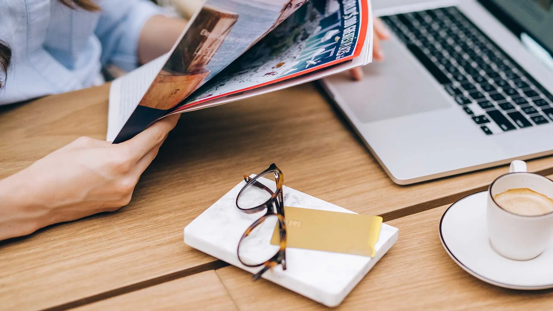 vrouw achter laptop leest een magazine