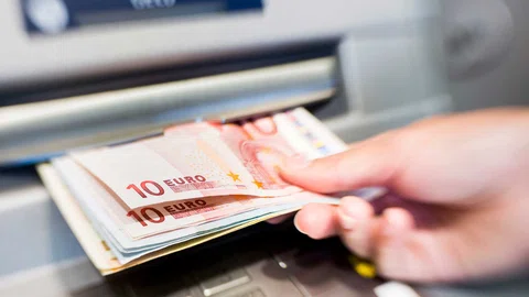 Een hand die geld uit de pinautomaat pakt