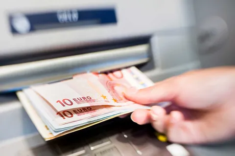 Een hand die geld uit de pinautomaat pakt