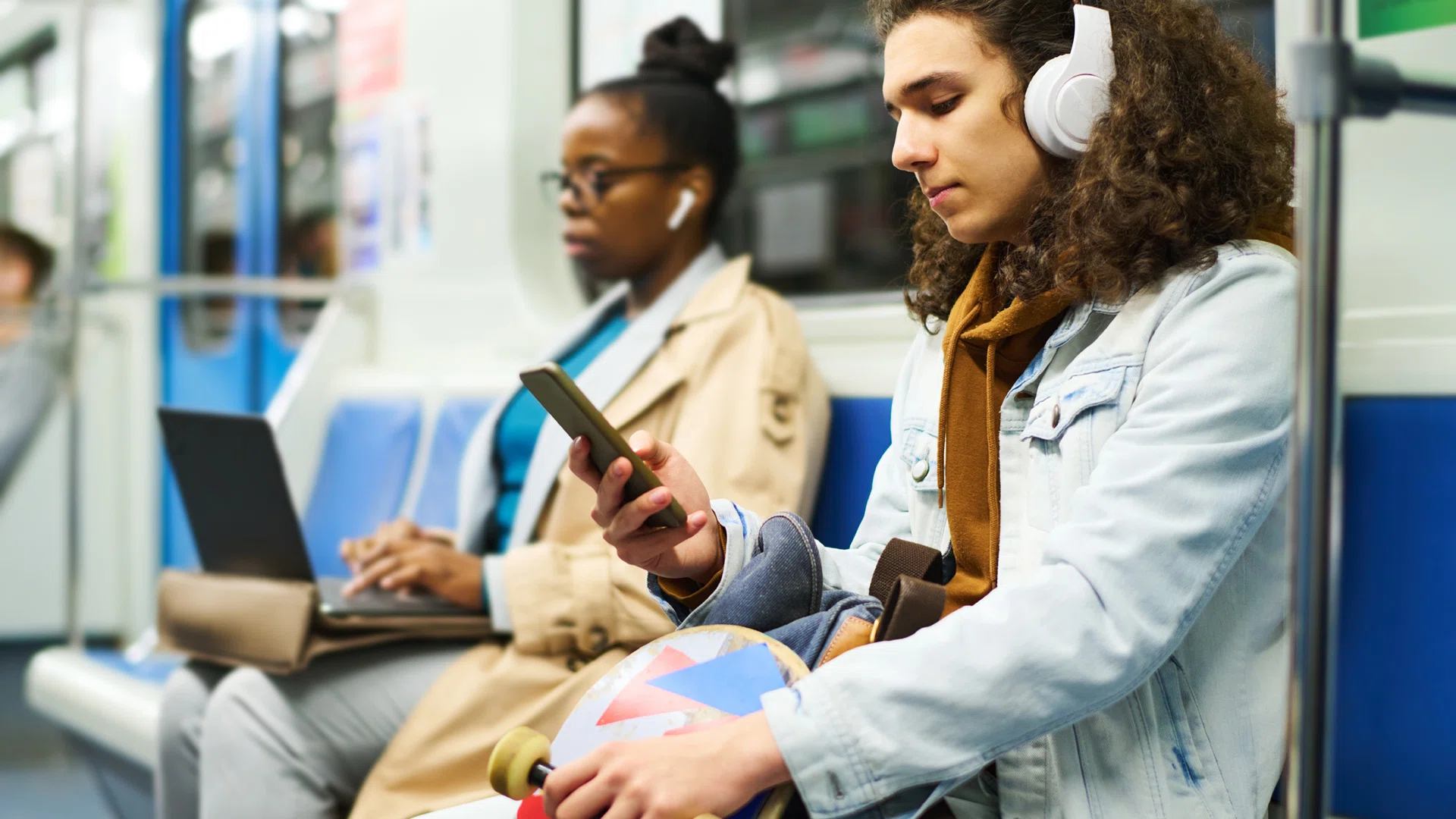 Man in het ov die op zijn telefoon zit te kijken met koptelefoon op