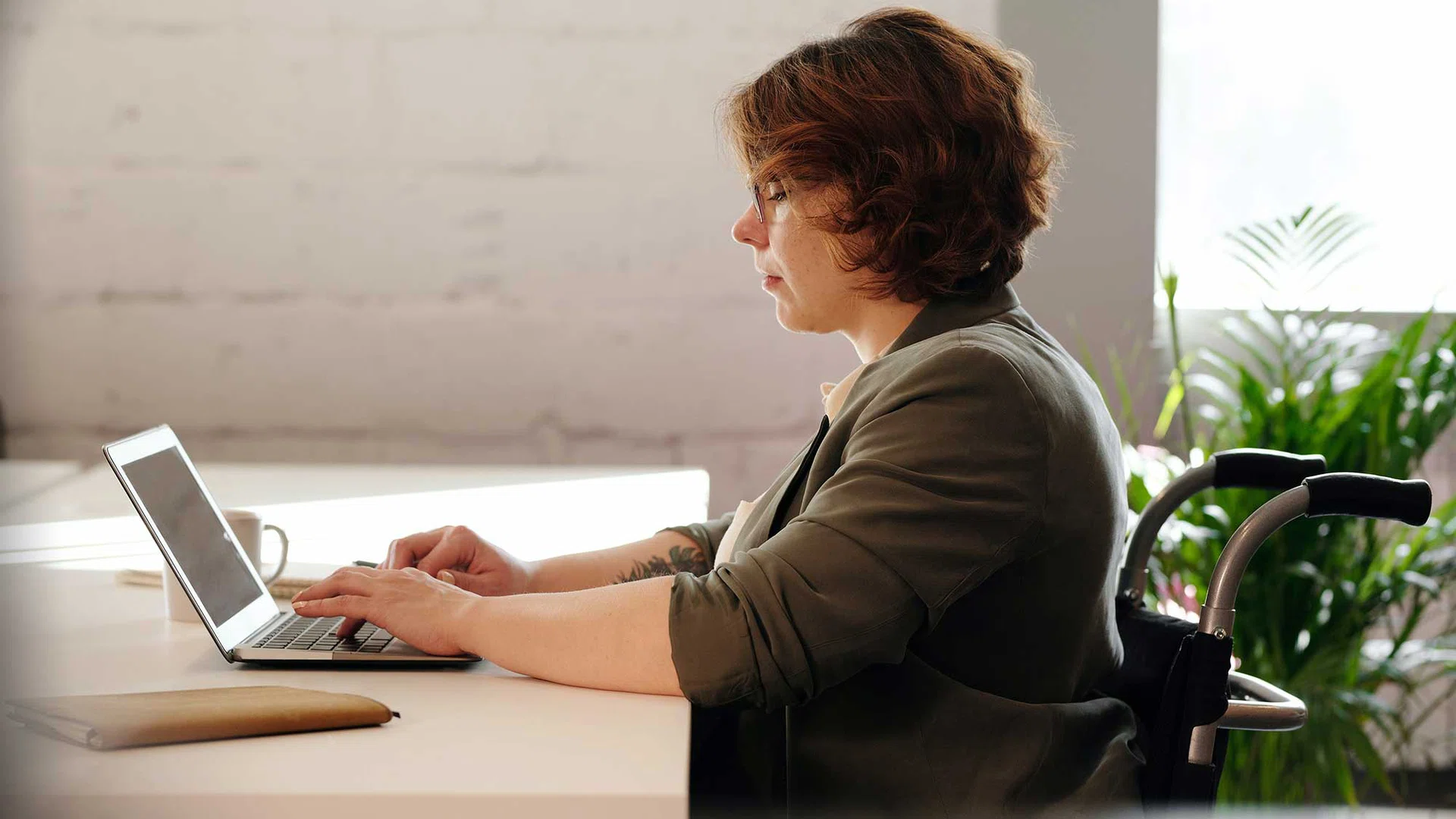 Vrouw in rolstoel aan het werk achter haar laptop