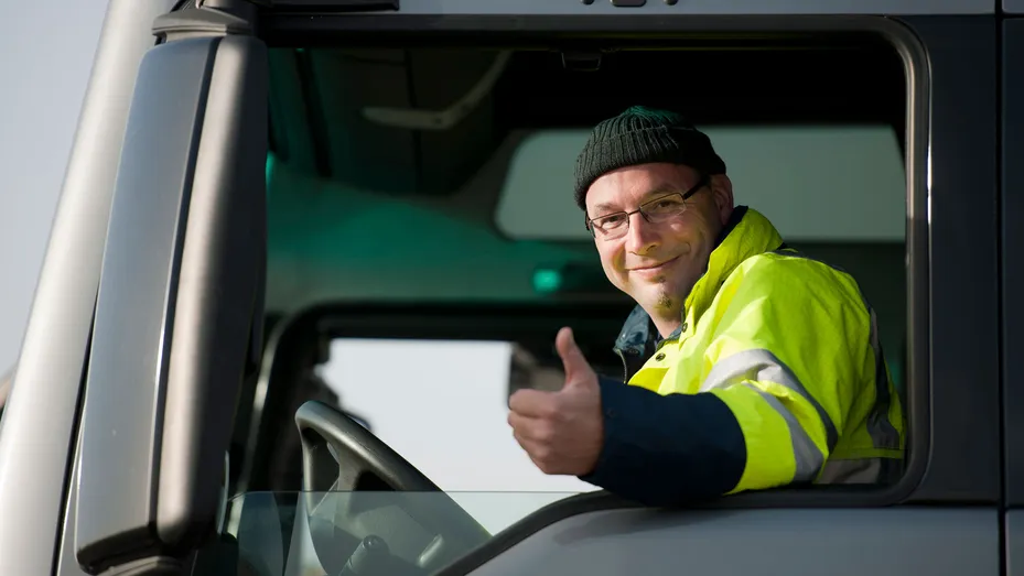 Truckchauffeur steekt zijn duim op vanachter zijn stuur